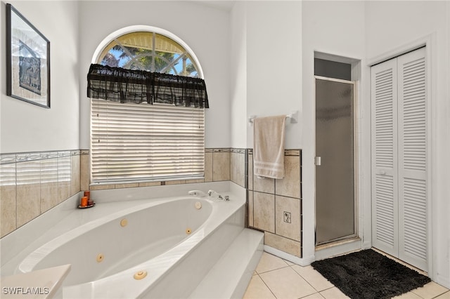 full bathroom featuring tile walls, a closet, a stall shower, a jetted tub, and tile patterned floors