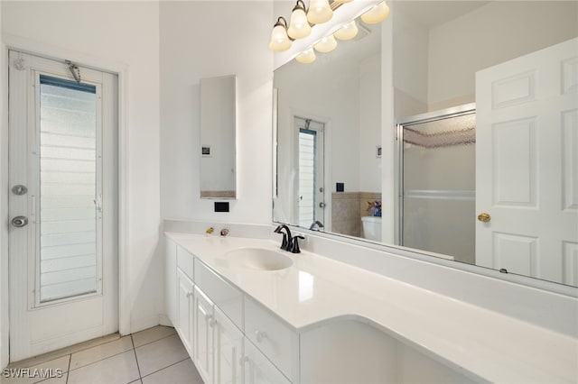 bathroom with a shower with shower door, tile patterned flooring, a chandelier, and vanity