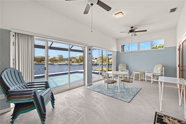 sunroom / solarium featuring a water view, ceiling fan, and visible vents