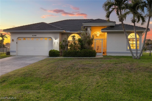 view of front of property featuring stucco siding, concrete driveway, an attached garage, a front yard, and a tiled roof