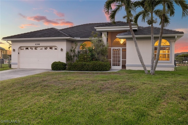 view of front of house featuring a garage, fence, driveway, a lawn, and stucco siding