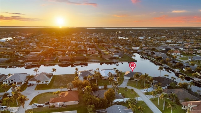 aerial view at dusk featuring a water view and a residential view