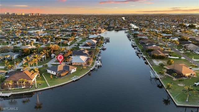 aerial view at dusk with a water view and a residential view