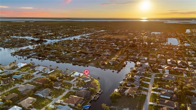 aerial view at dusk featuring a water view and a residential view