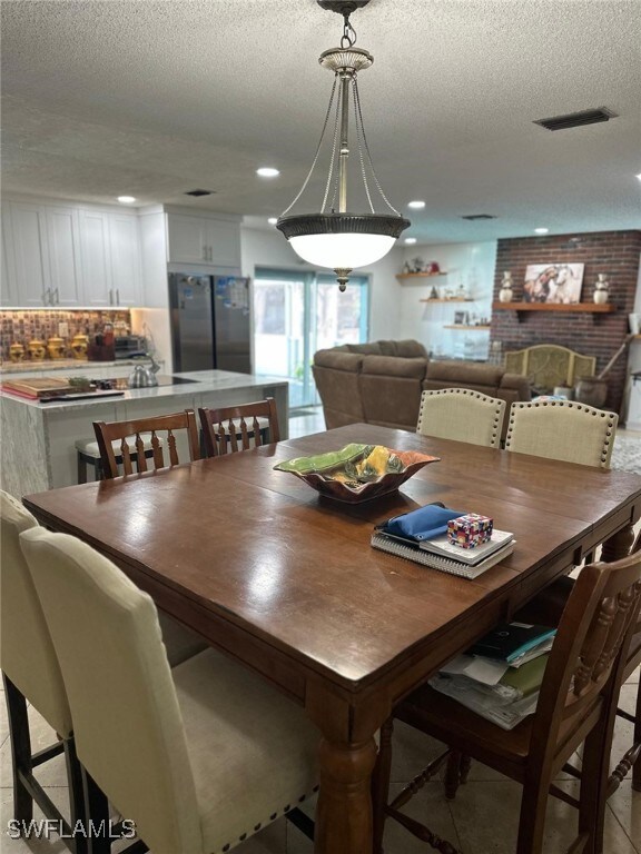 dining area with light tile patterned floors, visible vents, recessed lighting, and a textured ceiling