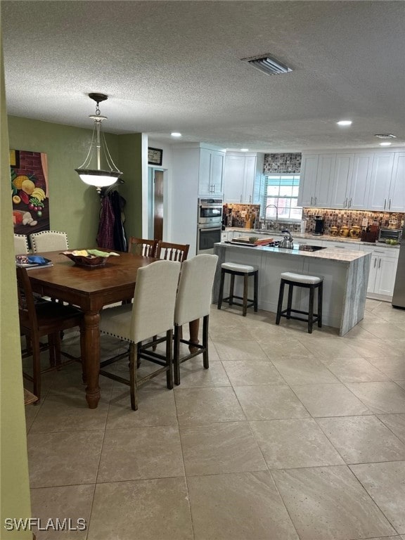 dining space featuring visible vents and a textured ceiling