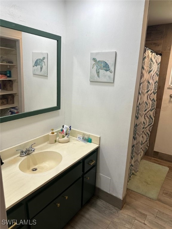 bathroom featuring curtained shower, vanity, baseboards, and wood finished floors