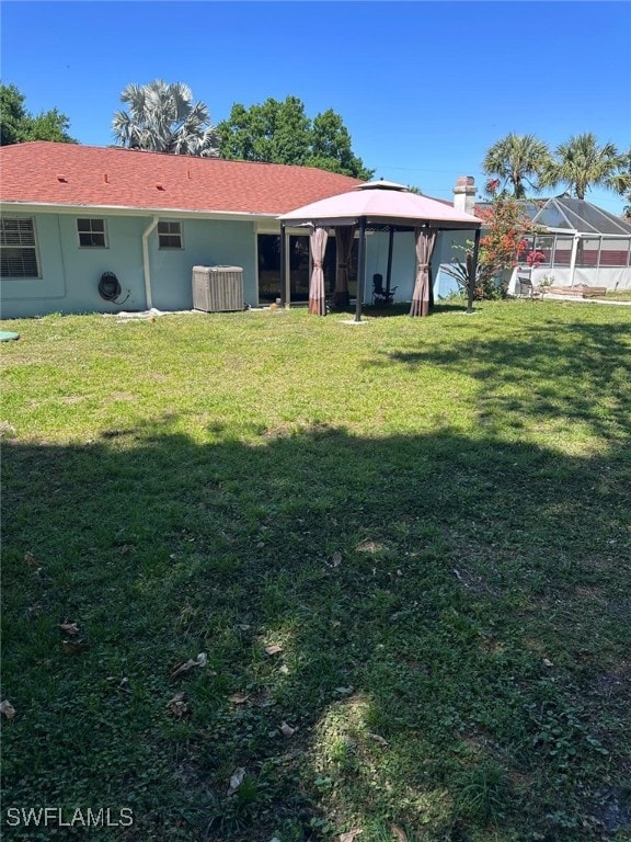 rear view of property featuring a gazebo and a yard