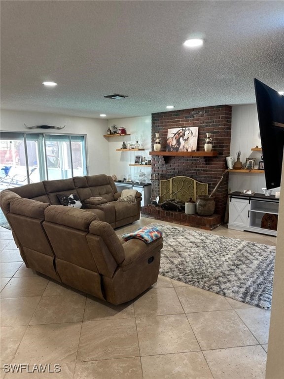 living room featuring tile patterned flooring, a brick fireplace, visible vents, and a textured ceiling