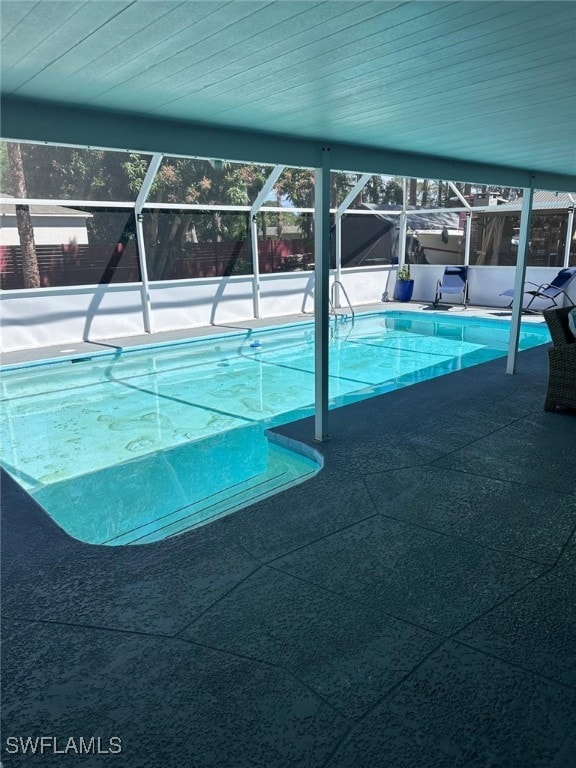 outdoor pool featuring glass enclosure and a patio area