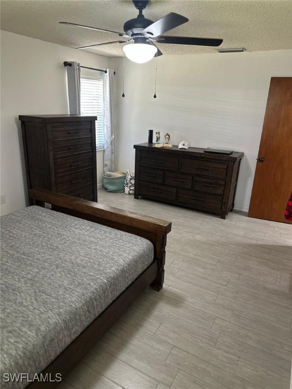 bedroom featuring visible vents, a textured ceiling, ceiling fan, and wood finished floors