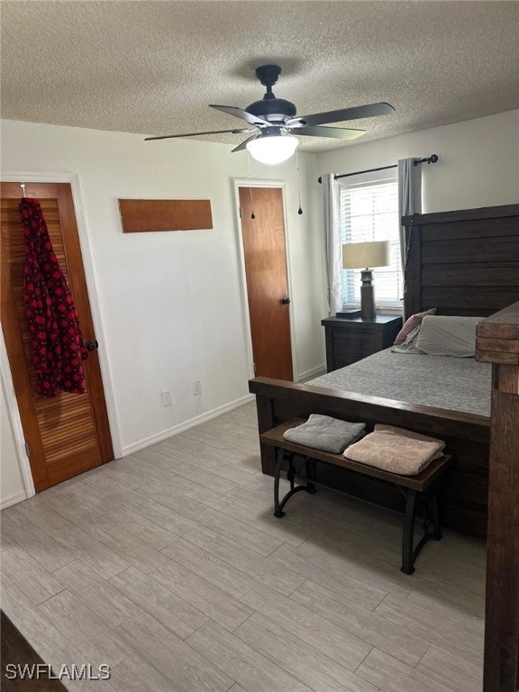 bedroom featuring baseboards, ceiling fan, a textured ceiling, and light wood-style floors