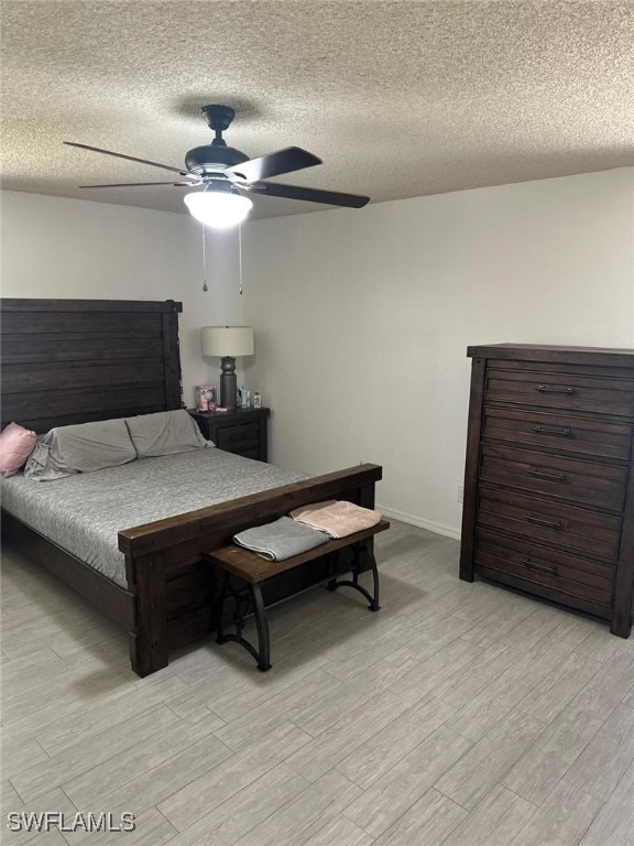 bedroom featuring light wood-type flooring, baseboards, a textured ceiling, and a ceiling fan