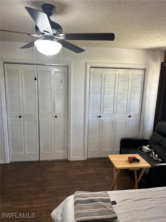 bedroom featuring dark wood finished floors, two closets, and a textured ceiling