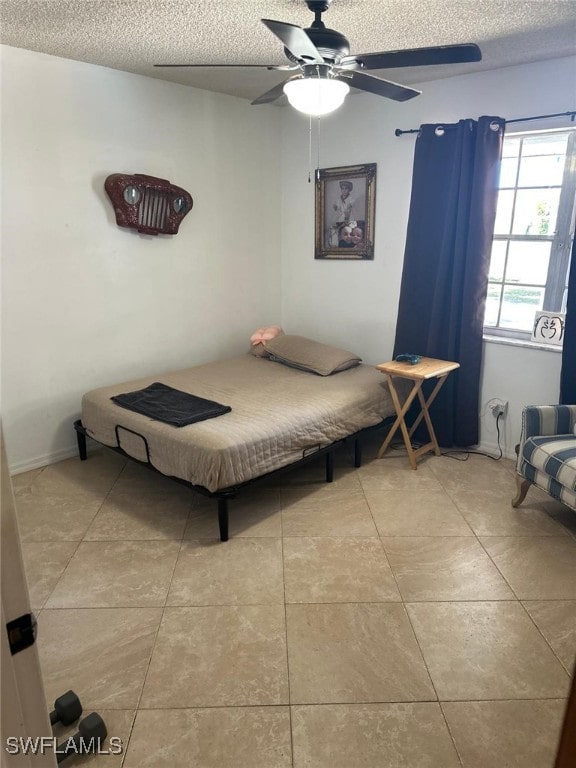 bedroom with tile patterned flooring, a ceiling fan, and a textured ceiling