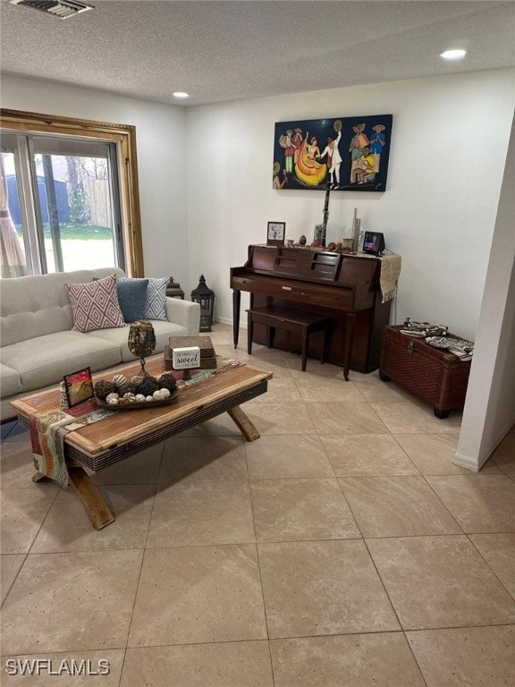 living room featuring recessed lighting, a textured ceiling, and light tile patterned floors