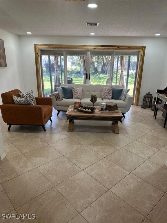 living area with light tile patterned flooring, recessed lighting, visible vents, and a textured ceiling