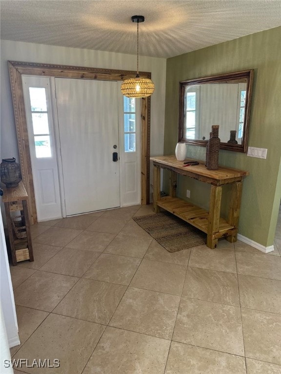 entrance foyer featuring light tile patterned floors, a textured ceiling, and baseboards