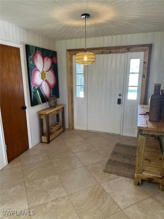 foyer entrance featuring a wealth of natural light, a textured ceiling, and light tile patterned floors