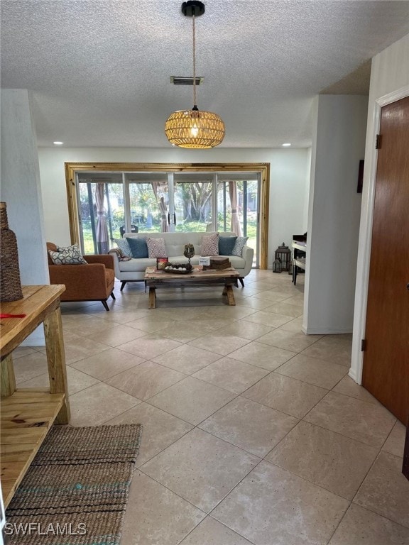 living area featuring light tile patterned floors, visible vents, and a textured ceiling