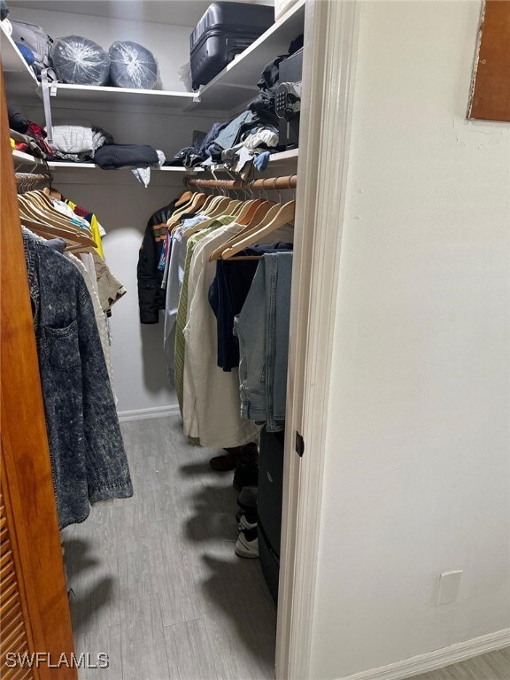 walk in closet with wood finished floors