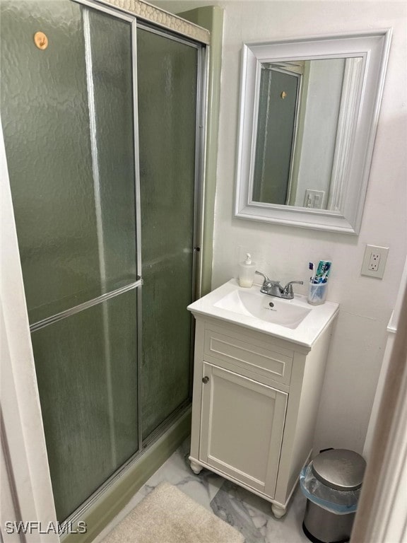 full bathroom with vanity, a shower stall, and marble finish floor