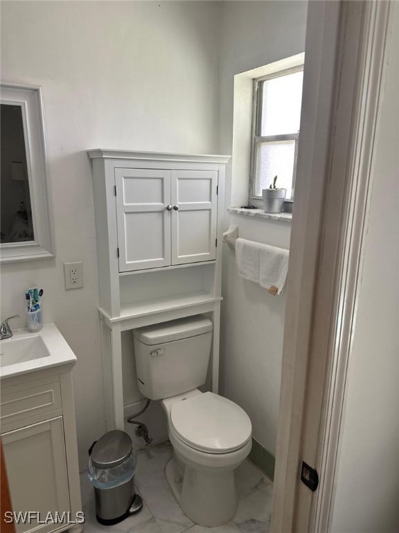 half bathroom with vanity, toilet, and marble finish floor