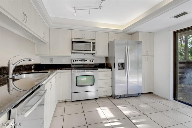 kitchen featuring visible vents, light tile patterned floors, dark stone countertops, stainless steel appliances, and a sink