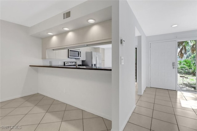 kitchen featuring visible vents, dark countertops, appliances with stainless steel finishes, white cabinets, and light tile patterned floors