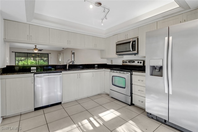 kitchen featuring a ceiling fan, dark stone countertops, a sink, appliances with stainless steel finishes, and light tile patterned floors