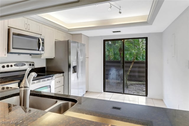 kitchen featuring visible vents, a tray ceiling, dark stone countertops, light tile patterned flooring, and stainless steel appliances