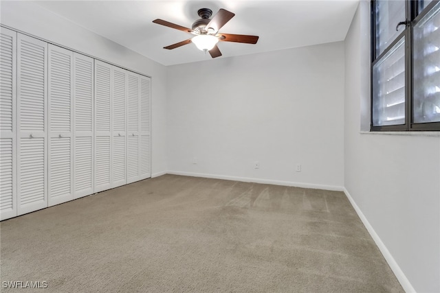 unfurnished bedroom featuring a closet, baseboards, carpet floors, and ceiling fan