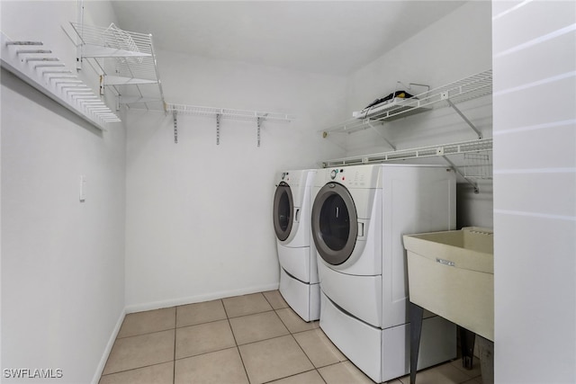 laundry room with baseboards, washing machine and dryer, light tile patterned floors, laundry area, and a sink