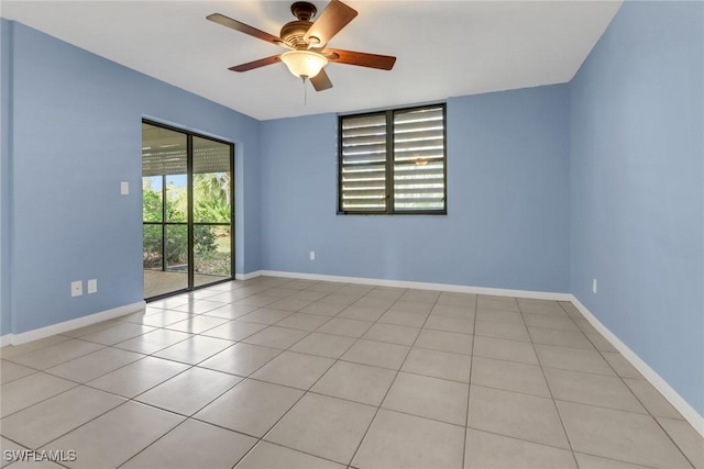 tiled empty room with baseboards and ceiling fan