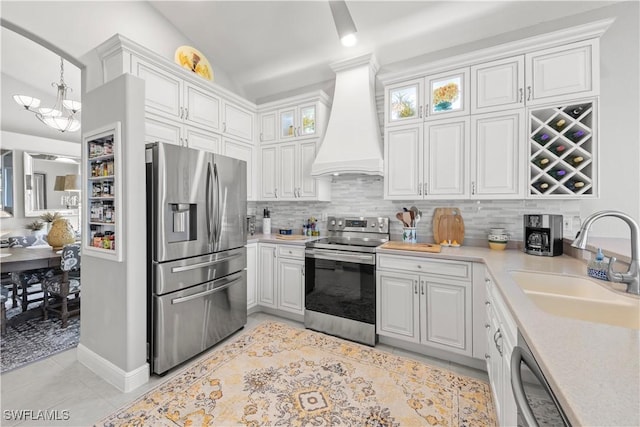 kitchen with light tile patterned floors, a sink, light countertops, custom range hood, and appliances with stainless steel finishes