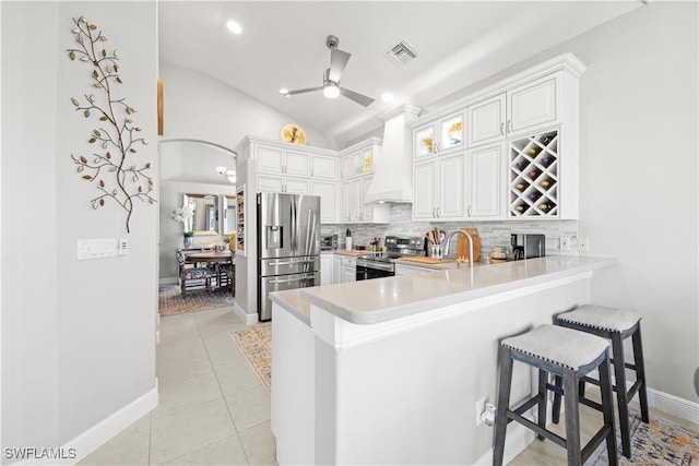 kitchen with visible vents, stainless steel appliances, a peninsula, a breakfast bar area, and custom exhaust hood