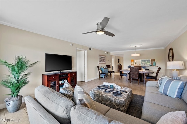 living room featuring light tile patterned floors, visible vents, a ceiling fan, baseboards, and ornamental molding