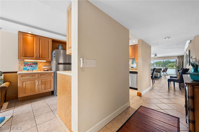 interior space with brown cabinets, light tile patterned floors, stainless steel appliances, tasteful backsplash, and light countertops