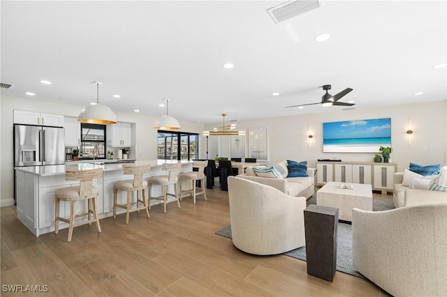 living room featuring recessed lighting, visible vents, and light wood-style flooring