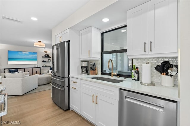 kitchen featuring a sink, decorative backsplash, appliances with stainless steel finishes, and open floor plan