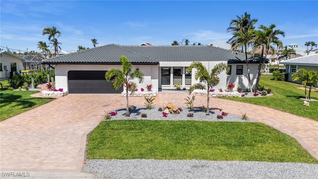 ranch-style home featuring a front yard, decorative driveway, a garage, and stucco siding