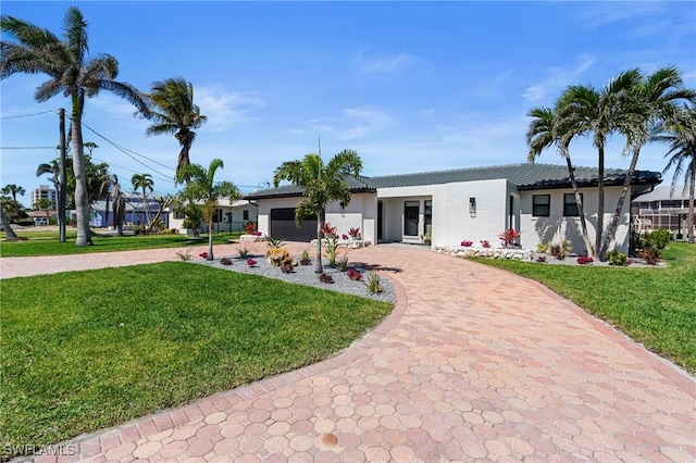 back of property with stucco siding, a lawn, a garage, and driveway