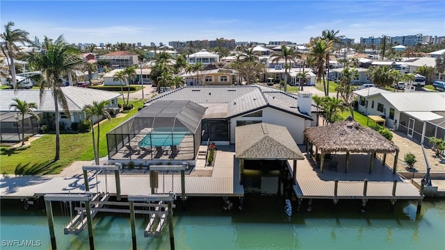 view of dock with a water view, a residential view, a fenced in pool, boat lift, and a lanai