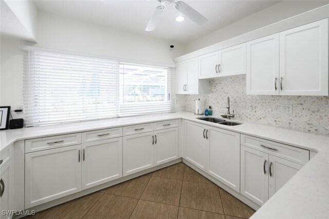 kitchen with ceiling fan, tile patterned flooring, a sink, white cabinetry, and backsplash