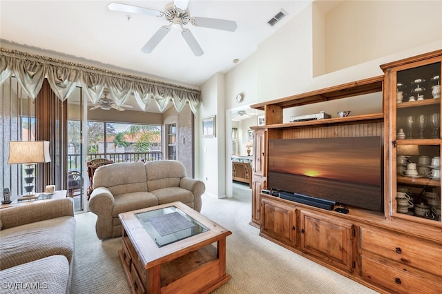 living area featuring ceiling fan, a high ceiling, visible vents, and light colored carpet