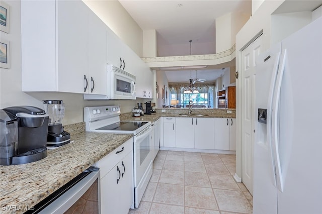 kitchen featuring light stone counters, white cabinets, a sink, light tile patterned flooring, and white appliances