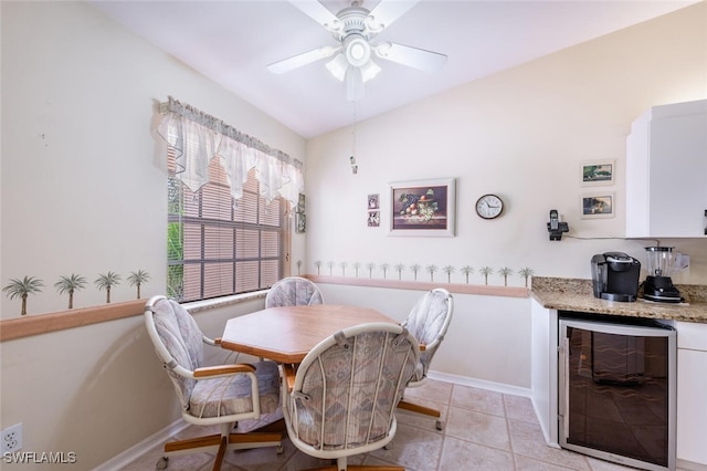 dining space with wine cooler, light tile patterned flooring, a ceiling fan, baseboards, and a bar