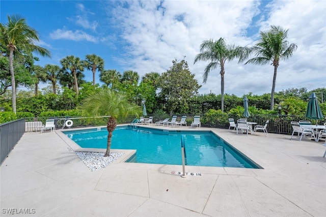 community pool with a patio and fence