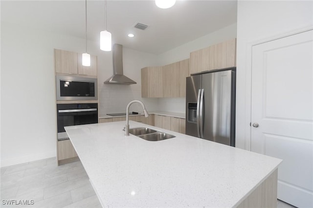 kitchen with light brown cabinets, a sink, wall chimney range hood, modern cabinets, and black appliances