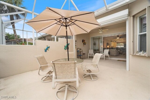 view of patio with a lanai, outdoor dining area, and ceiling fan